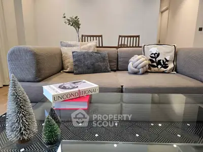 Stylish living room with modern sofa, decorative pillows, and glass coffee table in a cozy setting.