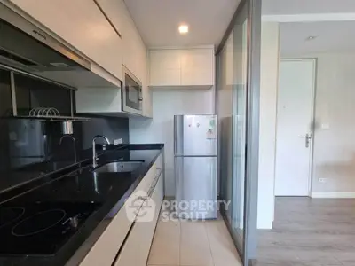 Modern kitchen with sleek appliances and black countertops in a compact layout.