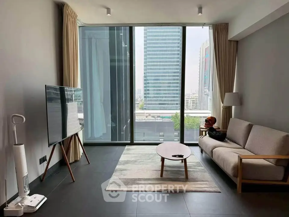 Modern living room with floor-to-ceiling windows and city view, featuring sleek furniture and minimalist decor.