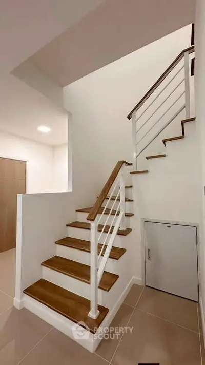 Modern staircase with wooden steps and sleek railing in a contemporary home interior.
