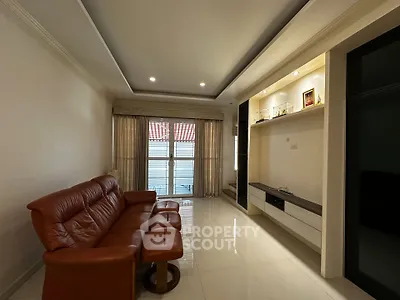 Spacious living room with elegant leather sofa and modern entertainment unit, featuring large windows for natural light.