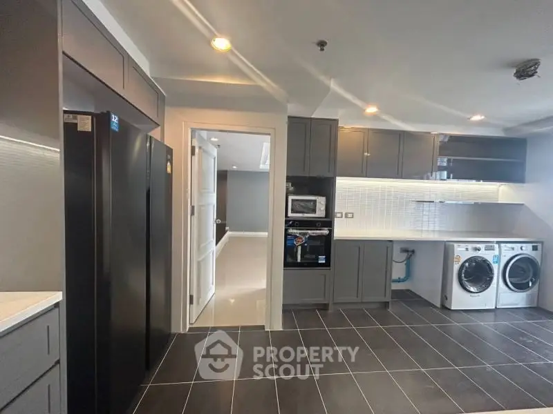 Modern kitchen with sleek appliances and laundry area in a stylish apartment.