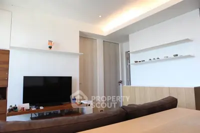 Modern living room with sleek design and large TV, featuring minimalist decor and stylish shelving.