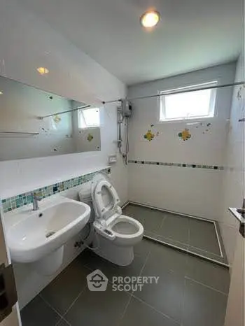 Modern bathroom with sleek fixtures and large mirror, featuring a spacious shower area.