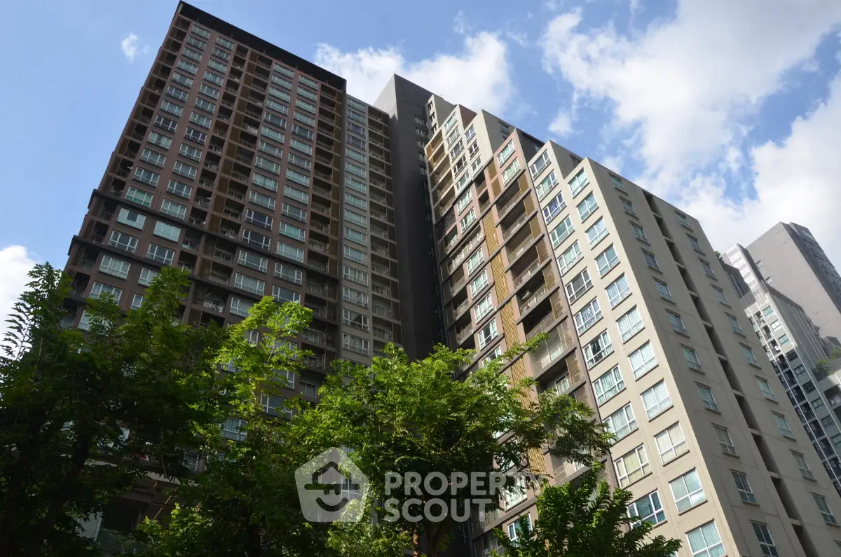 Modern high-rise residential building with lush greenery and clear blue sky.