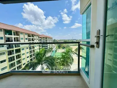 Spacious balcony with stunning view of lush greenery and modern apartment buildings.