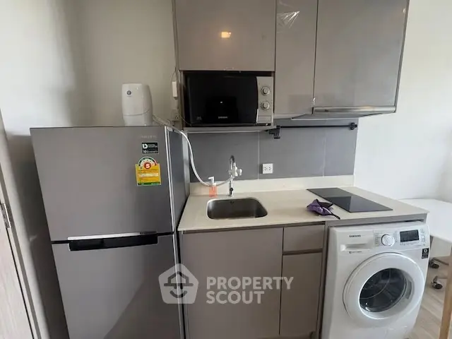 Modern compact kitchen with appliances including fridge, microwave, and washing machine.