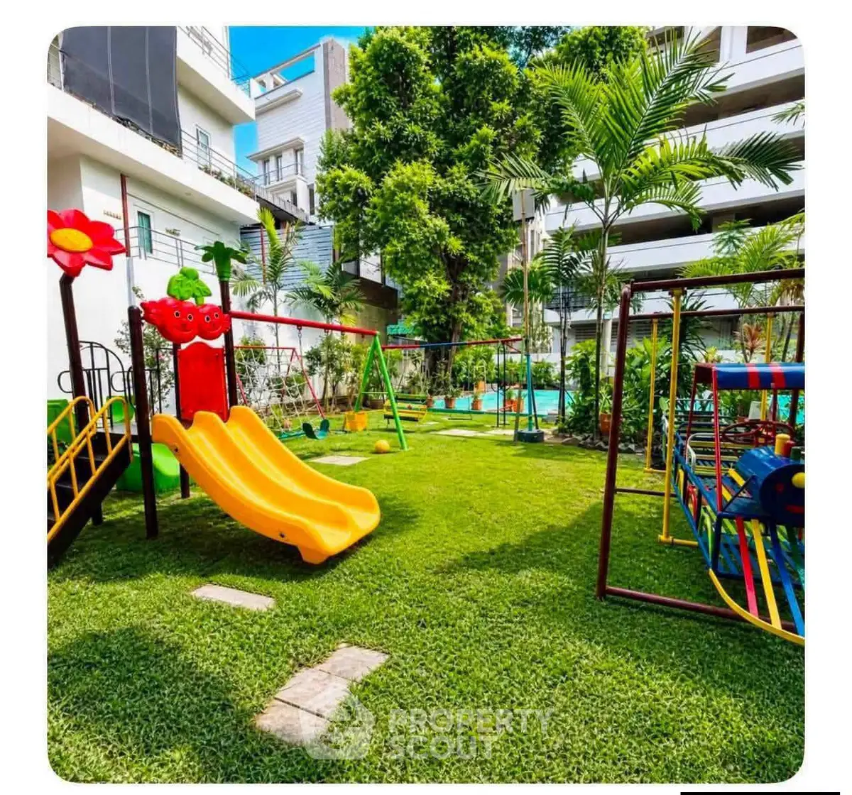 Vibrant residential playground with slides and swings in lush green garden setting.