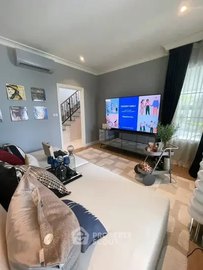 Stylish living room with modern decor and large TV, perfect for relaxation.