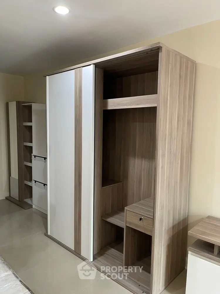 Modern bedroom with sleek wooden wardrobe and ample storage space.