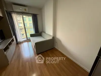 Cozy living room with wooden flooring and a large window for natural light.