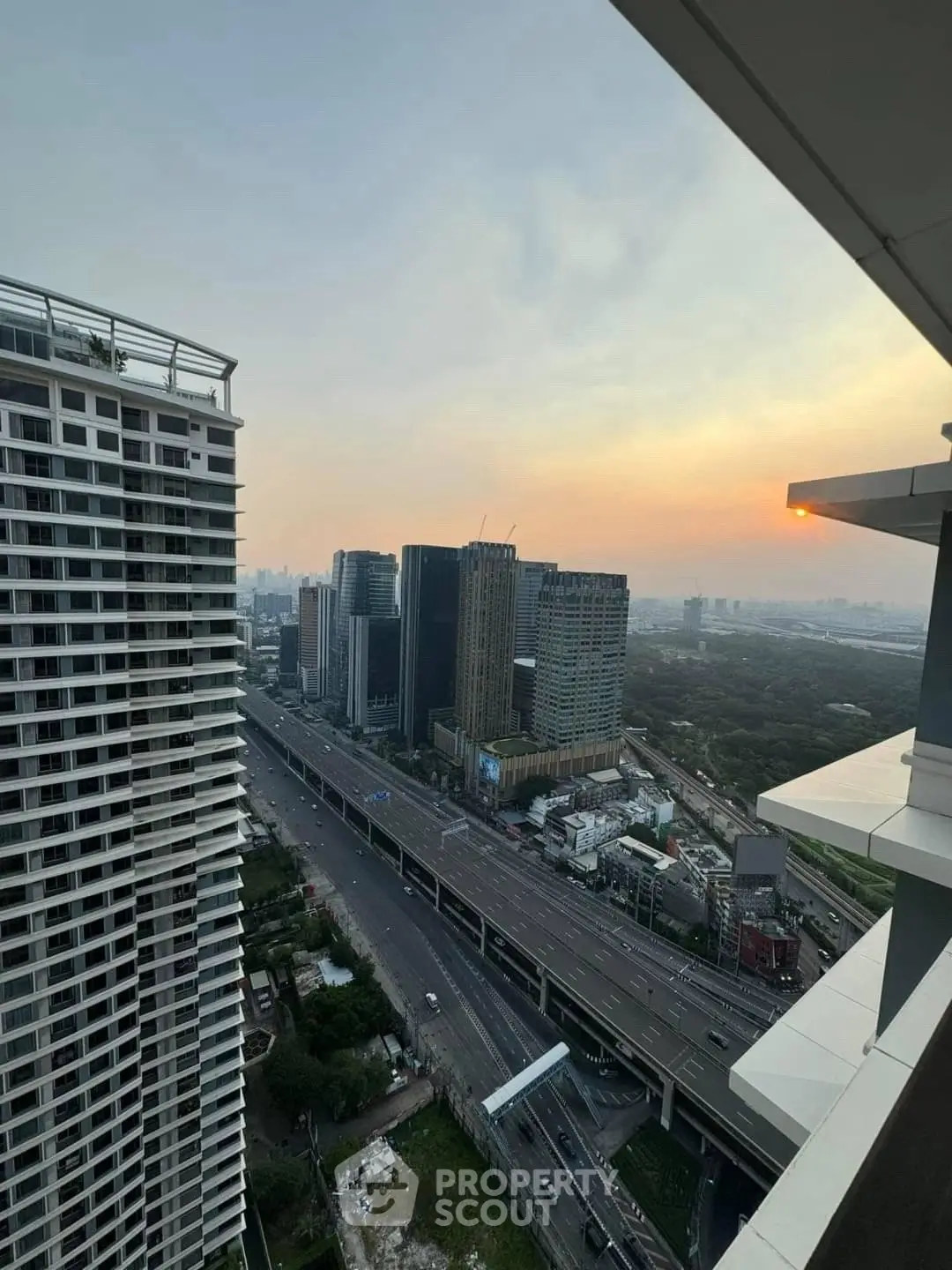 Stunning cityscape view from high-rise balcony at sunset, showcasing modern urban living.