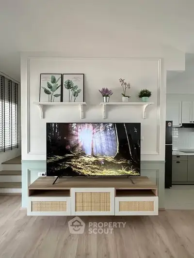 Modern living room with stylish TV setup and decorative shelves, featuring a serene and inviting atmosphere.