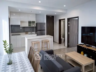 Modern open-plan living room and kitchen with sleek design and natural light.