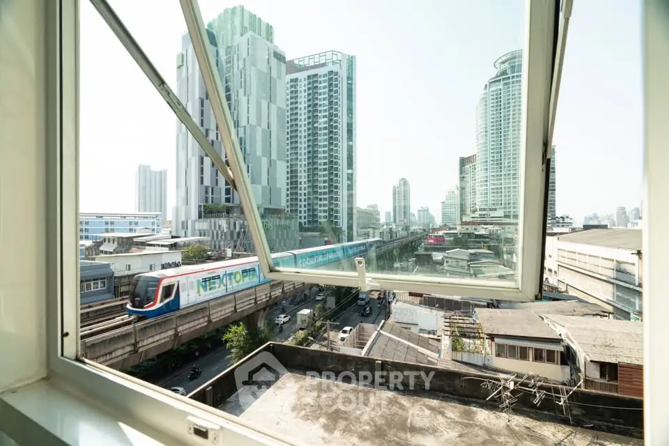 Stunning cityscape view from open window showcasing urban skyline and train, perfect for city living enthusiasts.