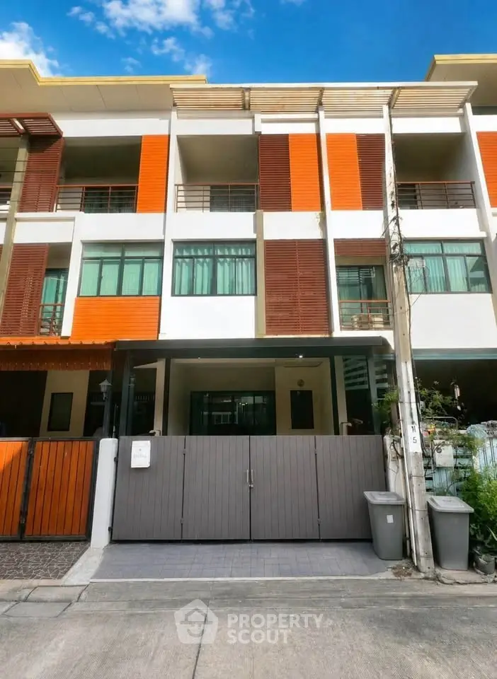 Modern townhouse exterior with vibrant orange accents and gated entrance