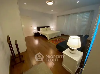Spacious bedroom with elegant decor and cozy lighting, featuring a comfortable bed and stylish wooden flooring.