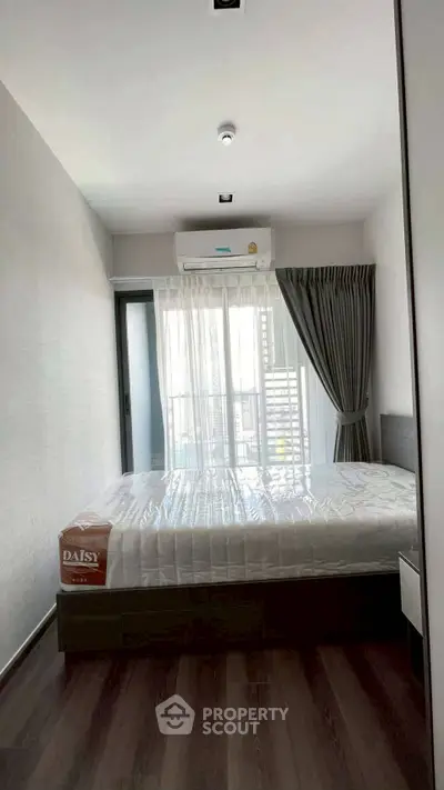 Modern bedroom with natural light, featuring a sleek design and air conditioning, perfect for urban living.