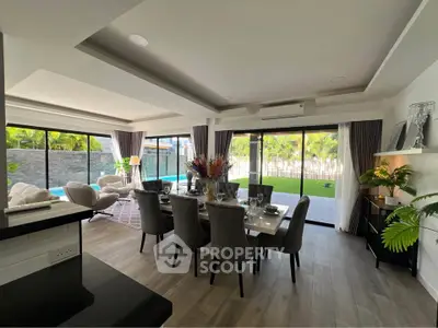 Luxurious open-plan living and dining area with pool view, featuring elegant decor and abundant natural light.