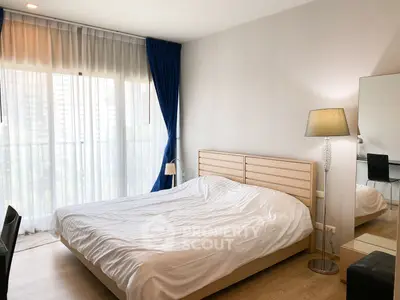 Spacious bedroom with large window and modern decor in a stylish apartment.