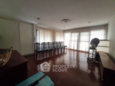 Spacious living room with wooden flooring and large windows for natural light.