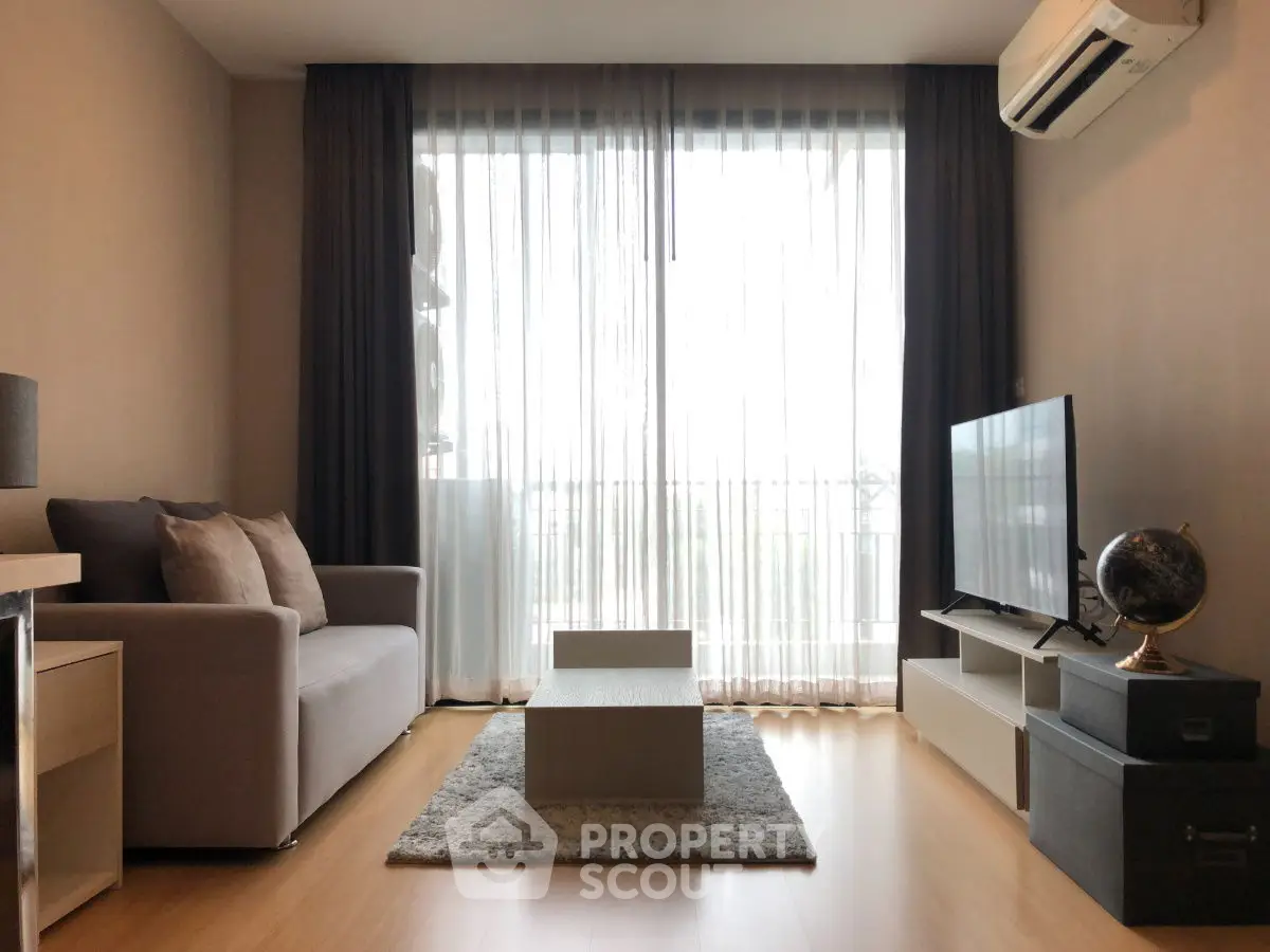 Modern living room with large window, cozy sofa, and sleek TV setup.