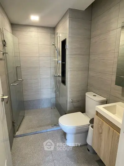 Modern bathroom with glass shower and sleek fixtures in contemporary home.