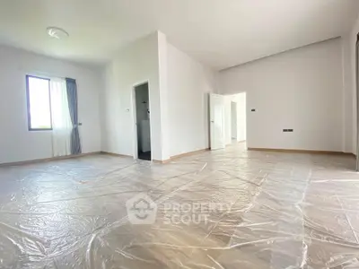 Spacious unfurnished room with natural light and plastic-covered floors, ready for customization.