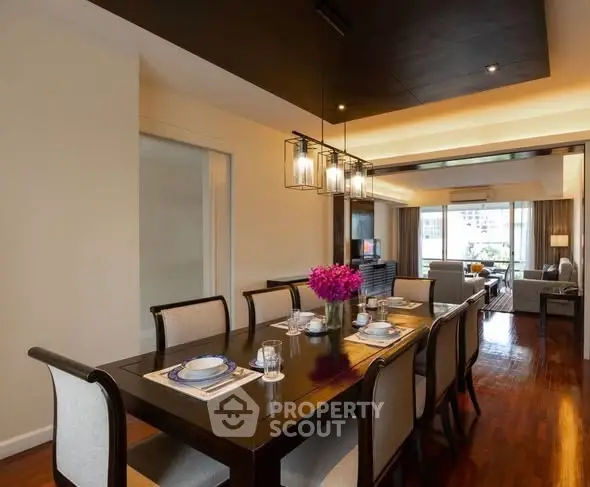 Elegant dining area with modern lighting and spacious living room view.