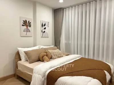 Cozy bedroom with modern decor and natural light, featuring stylish artwork and elegant curtains.