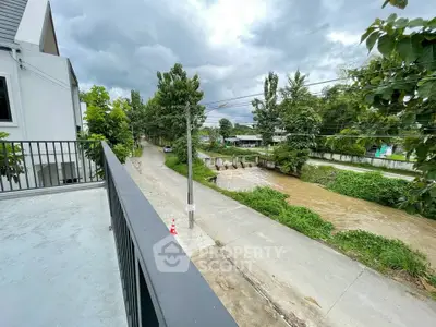 Charming balcony view overlooking lush greenery and serene river, perfect for nature lovers.