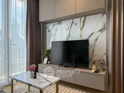 Modern living room with marble accents and large TV, featuring elegant decor and natural light.