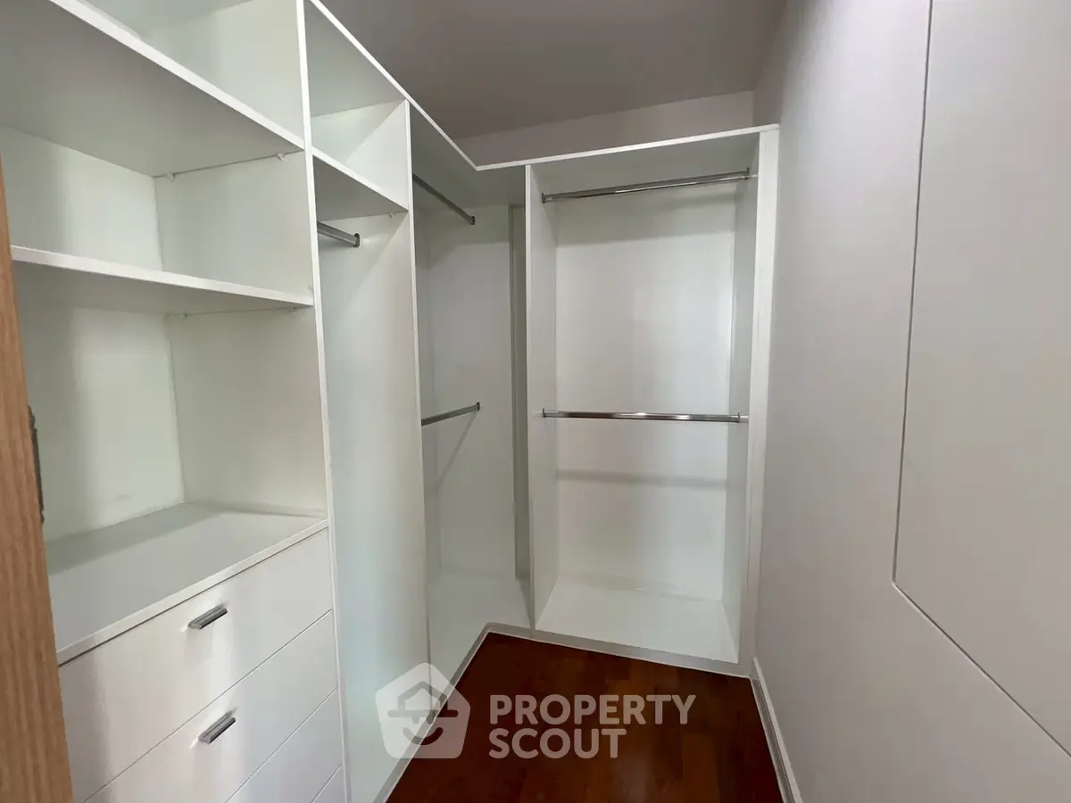 Spacious walk-in closet with modern white shelving and wooden flooring