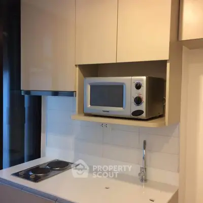 Modern kitchen with sleek appliances and minimalist design, featuring a built-in microwave and electric stove.