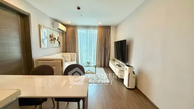 Modern living room with stylish decor, large TV, and natural light from floor-to-ceiling windows.