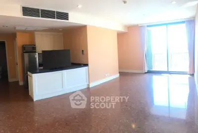 Spacious open-plan living area with large windows and modern kitchen in a bright apartment.