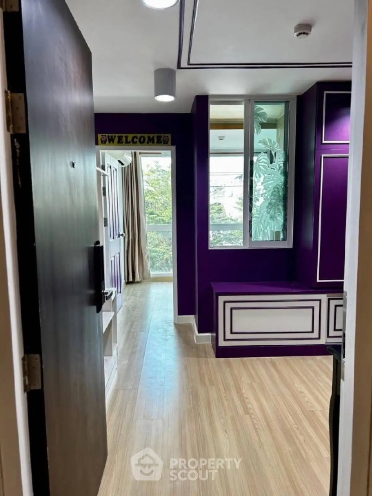 Stylish modern apartment entrance with vibrant purple accents and wooden flooring.