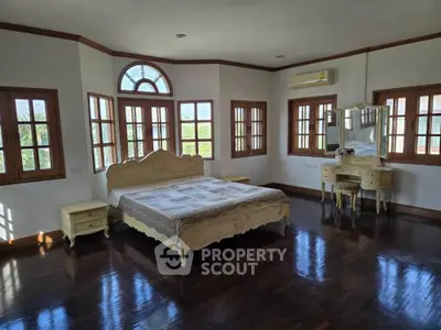 Spacious bedroom with elegant wooden furniture and large windows offering natural light.