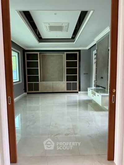 Spacious modern living room with elegant built-in shelving and marble flooring.