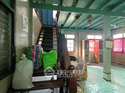 Spacious interior with wooden staircase and colorful bags, potential for renovation.