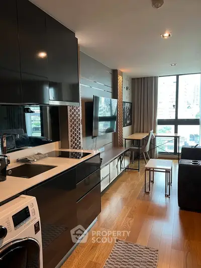 Modern open-layout kitchen and living area with sleek black cabinets and city view.