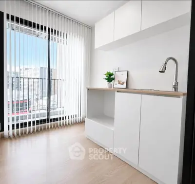 Modern minimalist kitchen with sleek white cabinets and large window view.