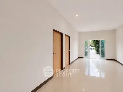 Spacious entrance hallway with glossy tiled floors and natural light.