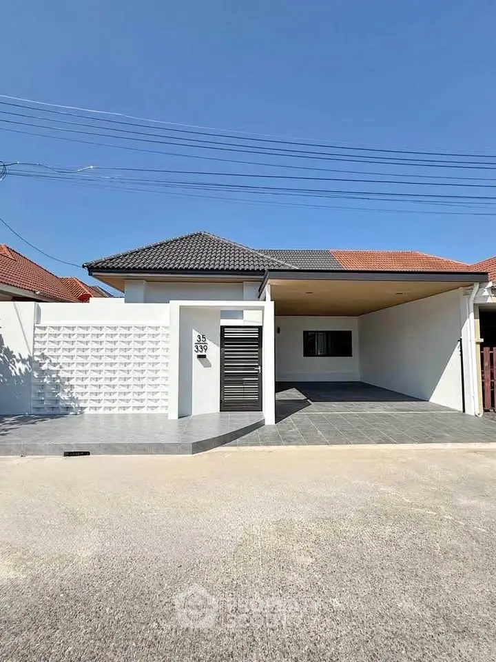 Modern single-story house with a sleek design and spacious driveway under a clear blue sky.