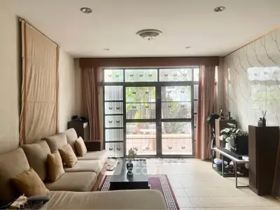 Spacious living room with large windows and cozy seating area, perfect for relaxation and entertaining.