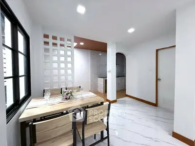 Modern dining area with sleek table and chairs, adjacent to stylish kitchen with open layout.