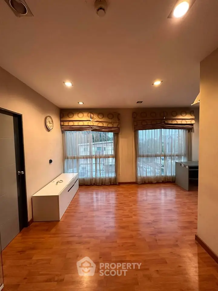 Spacious living room with wooden flooring and large windows for natural light.