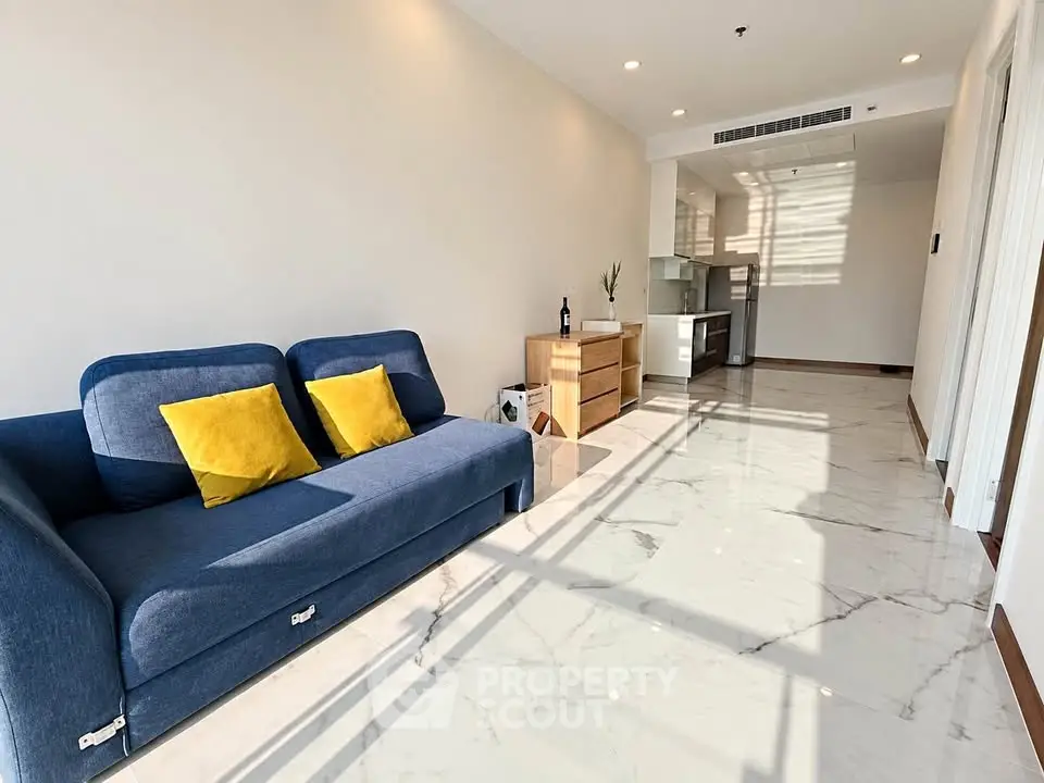 Spacious modern living room with sleek marble flooring and cozy blue sofa in bright apartment.