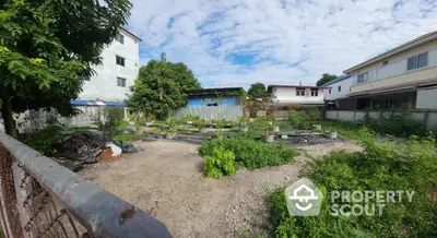 Spacious vacant lot with potential for development in a residential area, surrounded by greenery and neighboring houses.