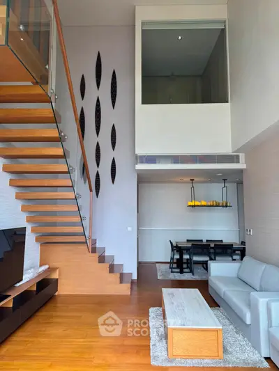Stunning modern living room with high ceilings, elegant staircase, and stylish dining area.